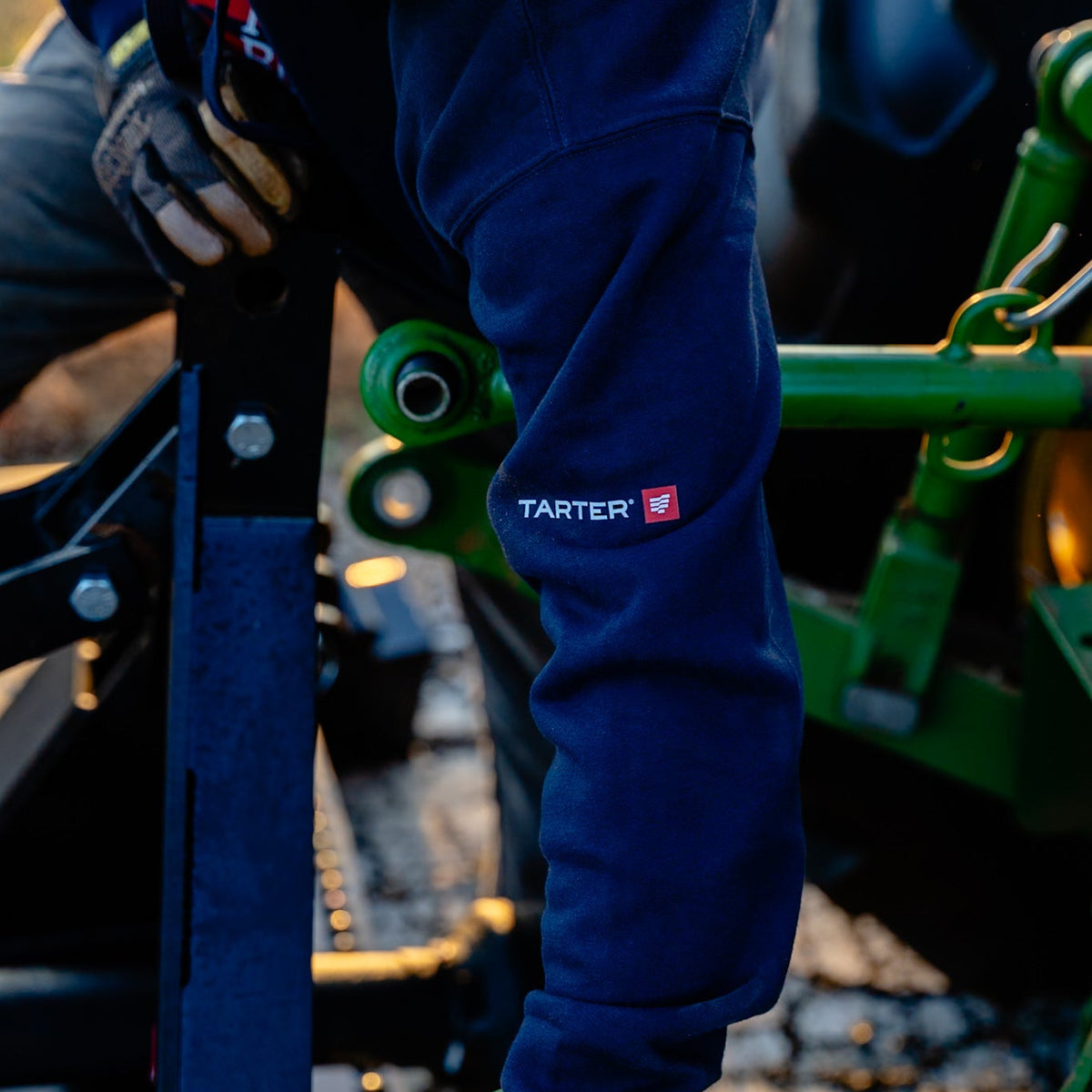 Person wearing blue pants with a Tarter logo on a green and black piece of equipment.